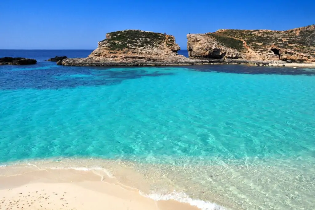 faixa de areia e mar ao fundo rochas naturais