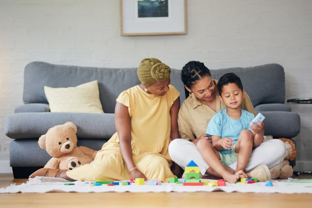 Casal de mulheres e criança brincando com brinquedos no chão