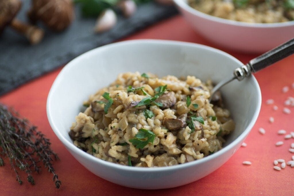 Risoto de cogumelo shiitake servido em prato fundo de porcelana branca