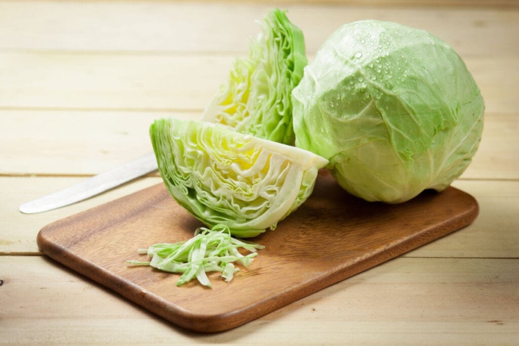 Repolho inteiro e repolho cortado em cima de tábua