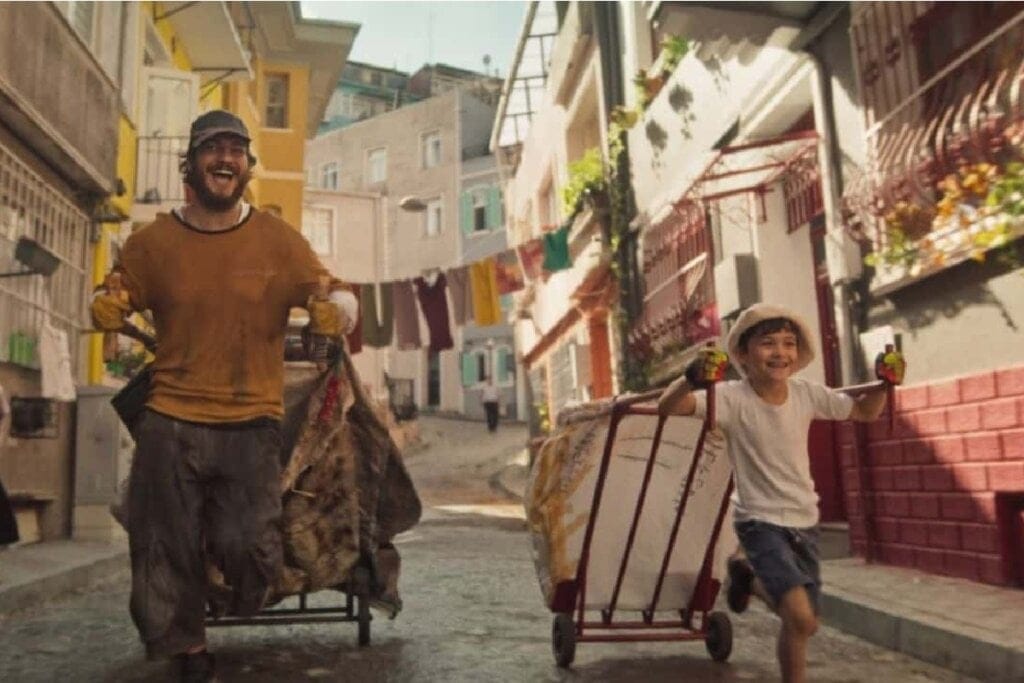 Homem e menino puxando carrinhos pelas ruas de um bairro popular, sorrindo um para o outro