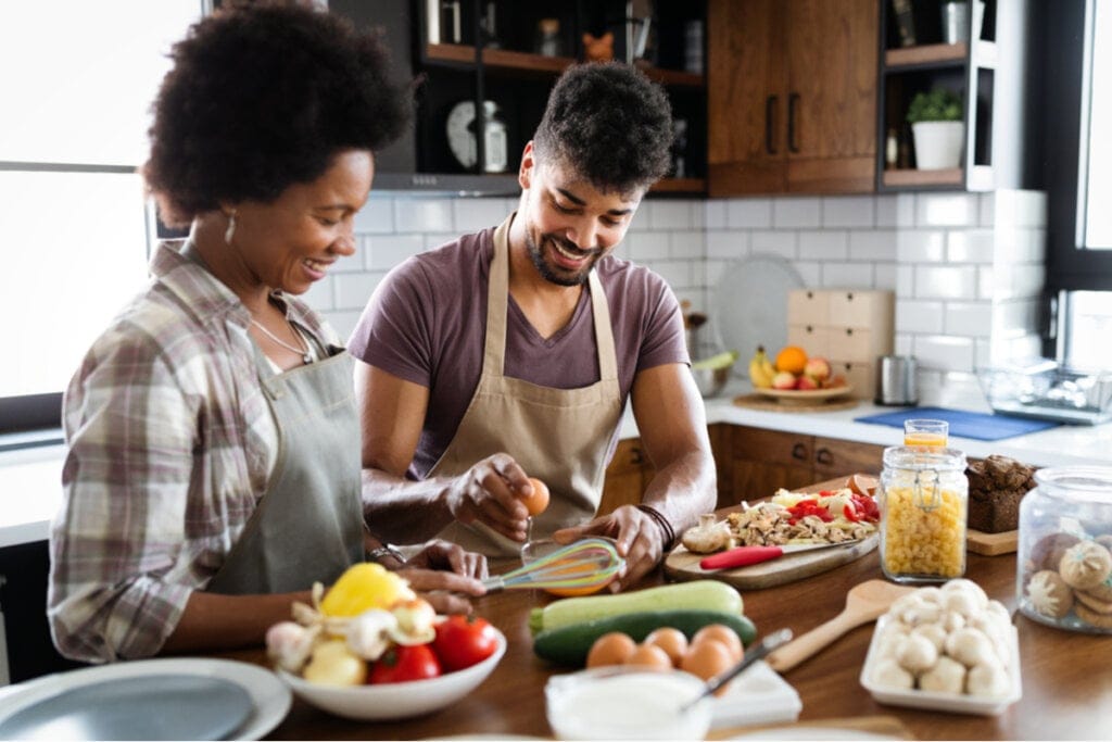 Homem e mulher de avental e na cozinha preparando comida