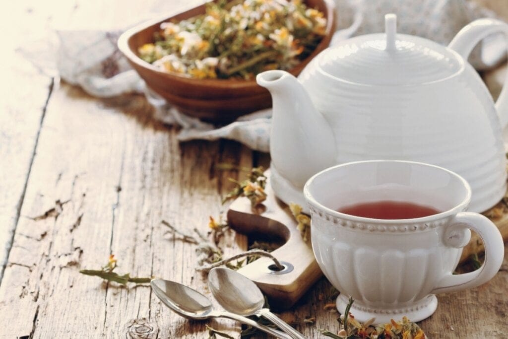 Chá de carqueja servido em xícara de porcelana em cima de mesa de madeira 