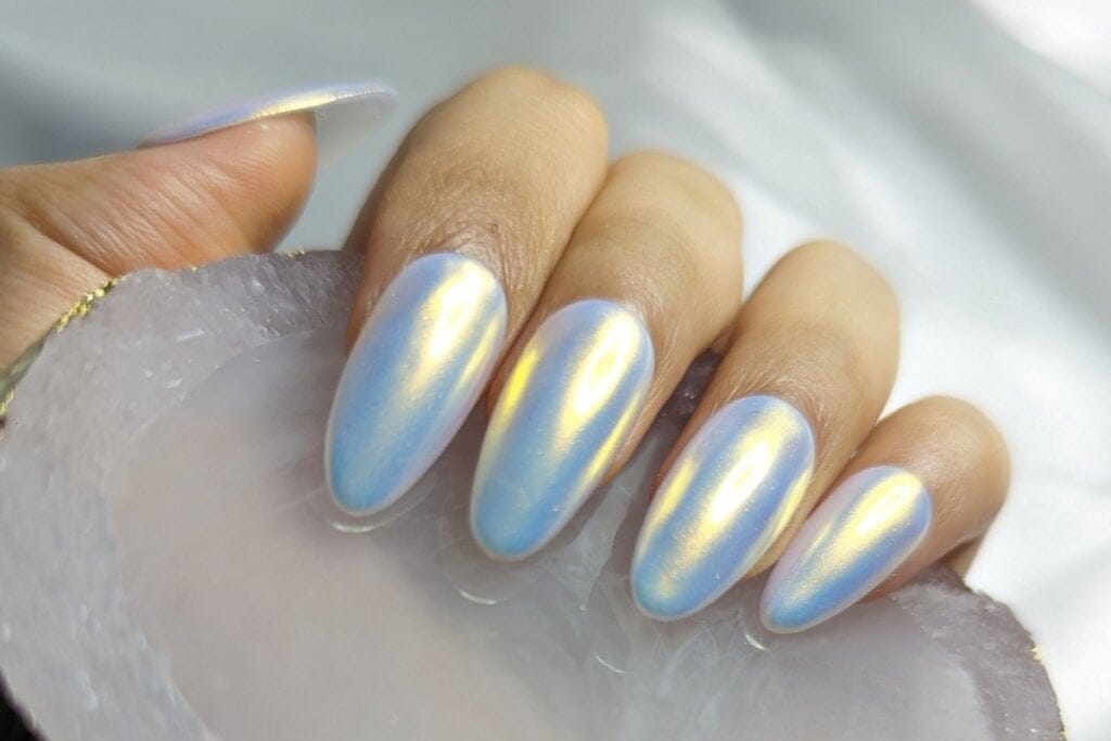 Mulher com unhas pintadas com esmalte cintilante azulado