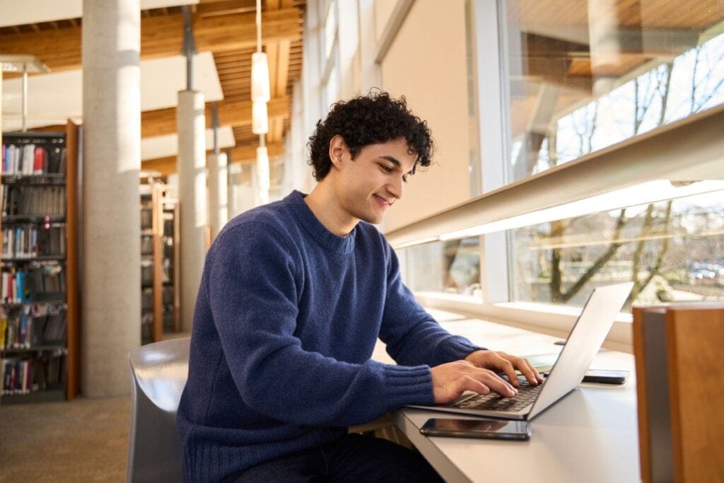 Homem estudando em biblioteca usando notebook