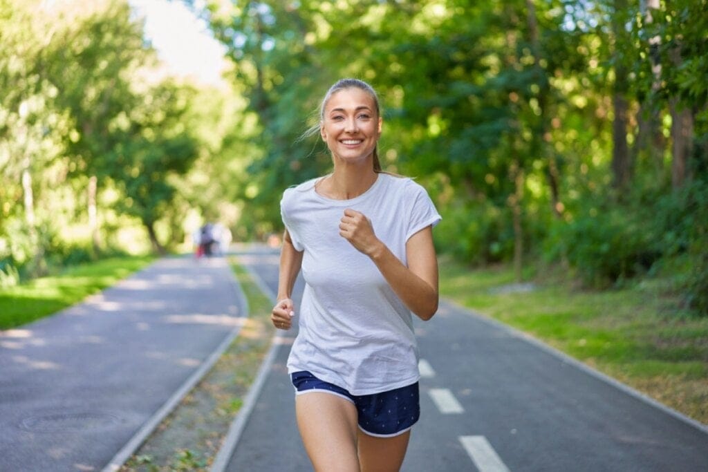 Mulher de camiseta branca e shorts correndo no parque