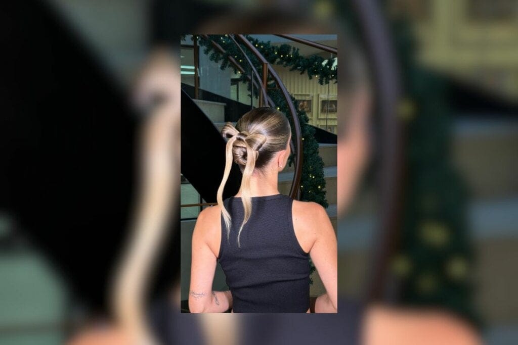 Mulher com um coque em formato de laço no cabelo e virada de costas 