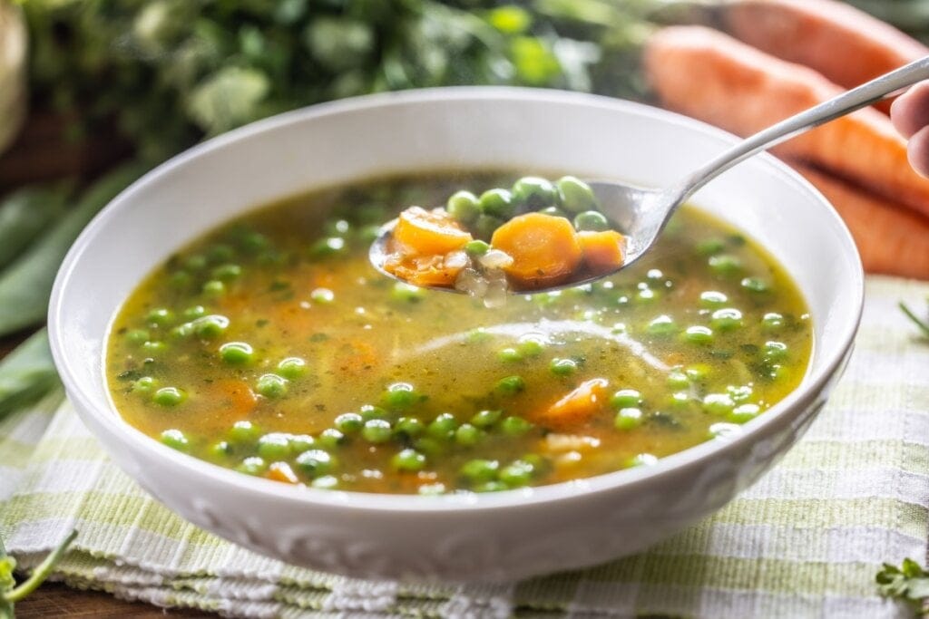 Recipiente branco com sopa de ervilha com cenoura