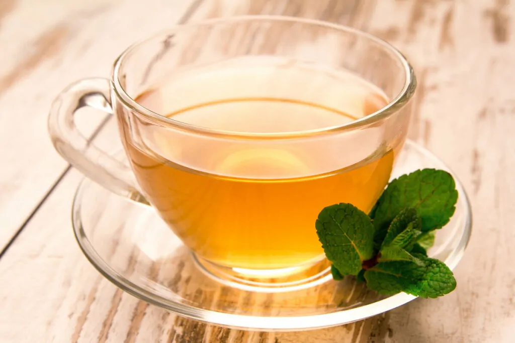 Xicara de vidro com chá em cima de uma mesa de madeira 