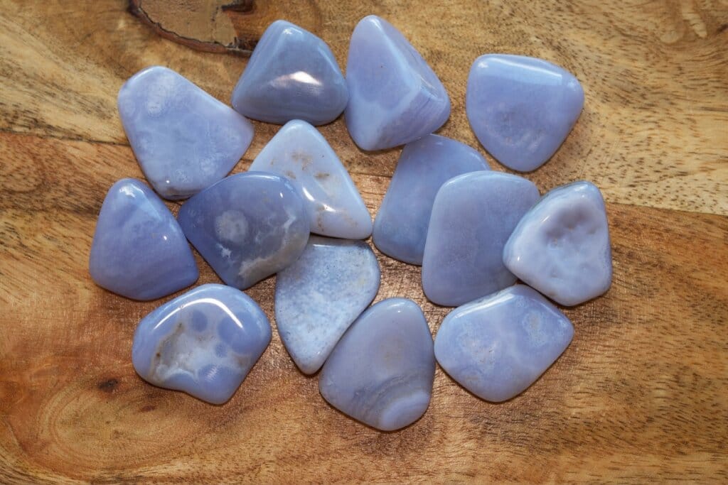 Pedras calcedônias em tons de roxo azulado em cima de mesa de madeira 