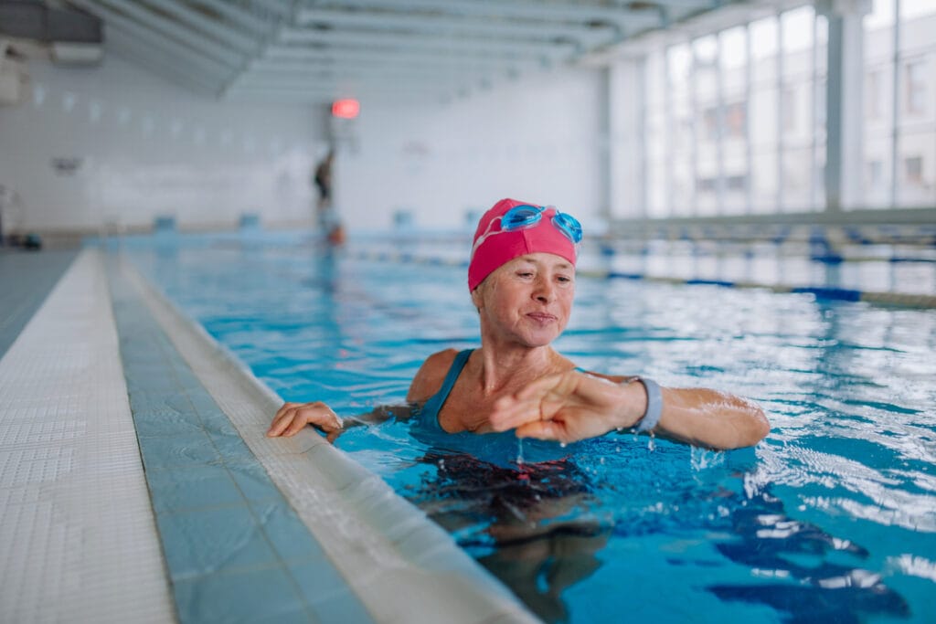 Mulher dentro de uma piscina olhando para um relógio