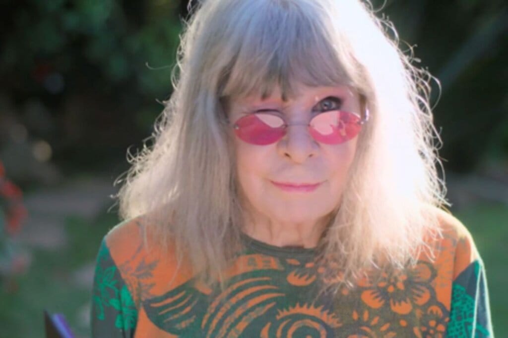 Rita Lee com os cabelos lisos, franja reta e fios brancos, usando óculos de sol rosa