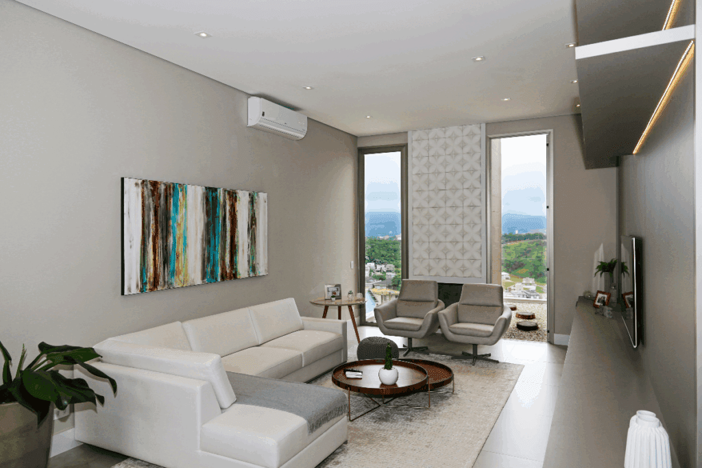 Sala de apartamento com sofá branco, com quadro colorido na parede e mesa de centro em madeira, com forro branco com luminárias