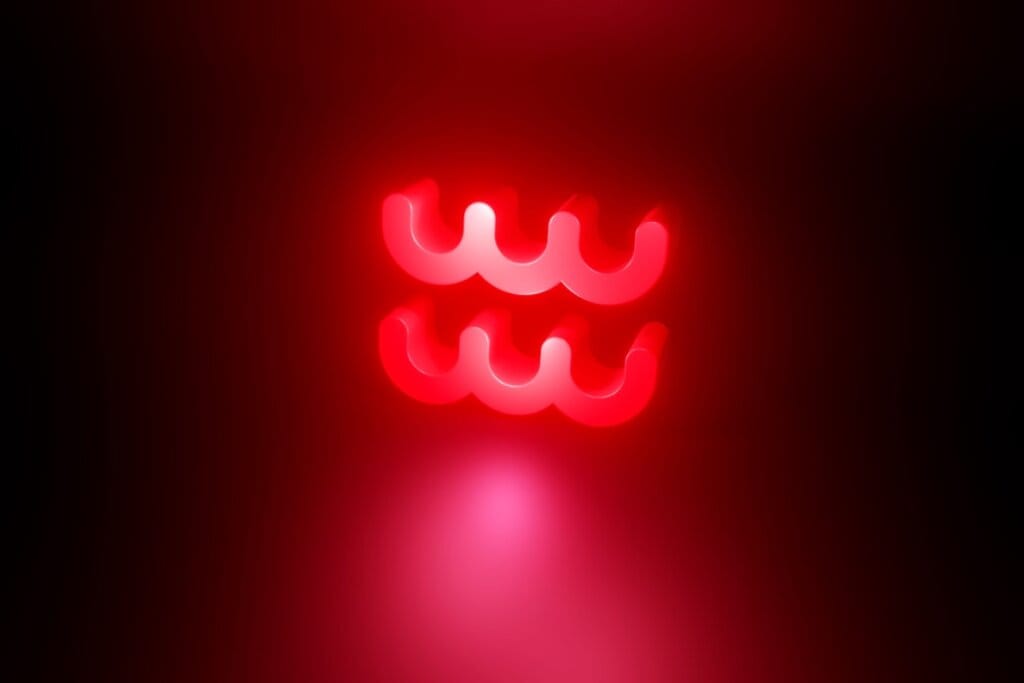 Ilustração em vermelho do símbolo do signo de signo de Aquário em fundo vermelho escuro