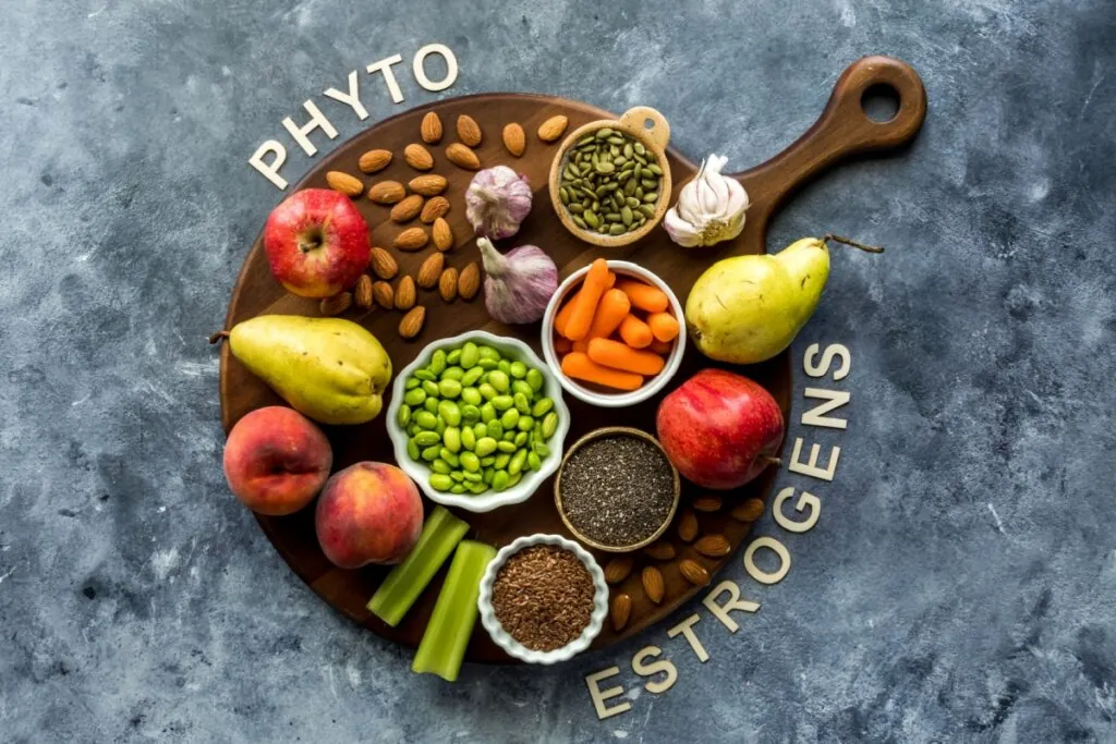 Tábua de madeira com alimentos ricos em fitoestrógenos como linhaça pera, alho e ao redor está escrito fitoestrógenos em inglês