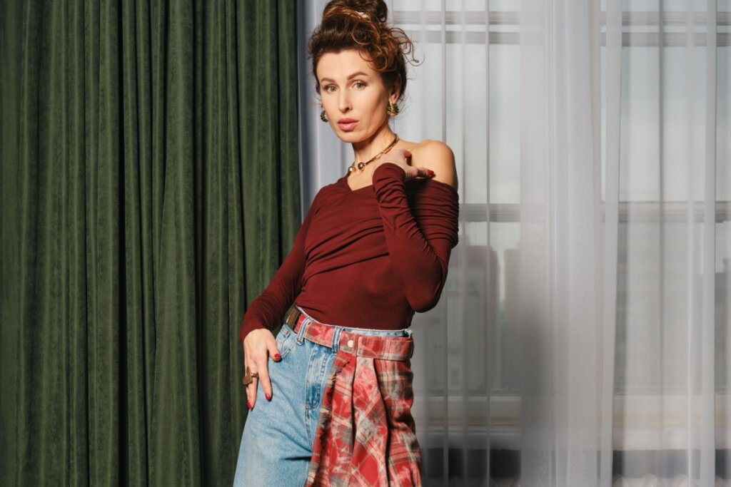 mulher de cabelo preso, blusa vinho, calça jeans e lenço vermelho na cintura