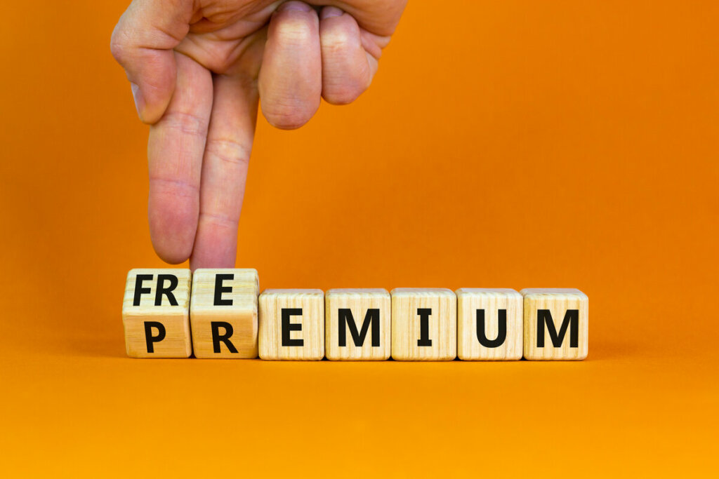 Dados de madeira escritos "freepremium" com dedos virando os primeiros dados, em fundo laranja