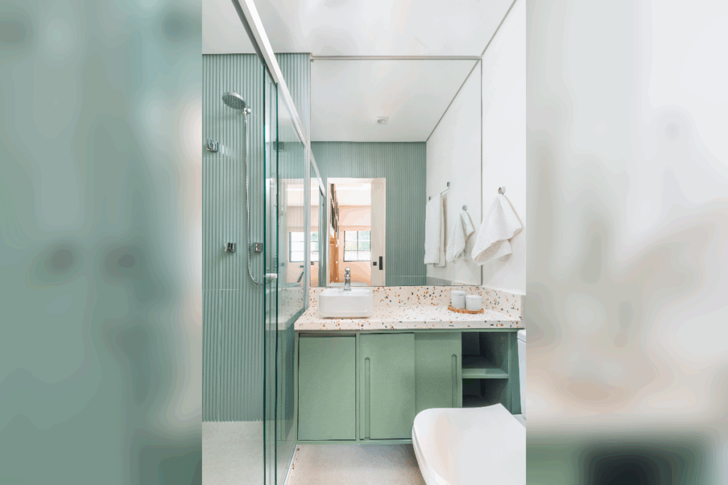 Banheiro com decoração em tons de verde e branco, com armário com pia em mármore e armário verde