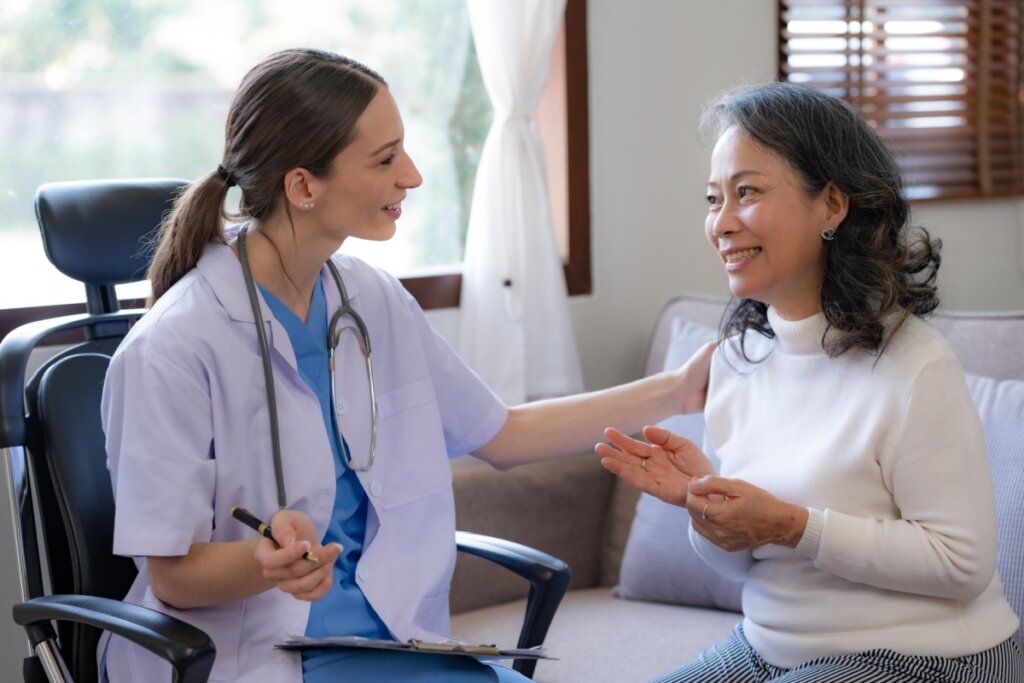 Médica e paciente sentadas, se olhando e sorrindo