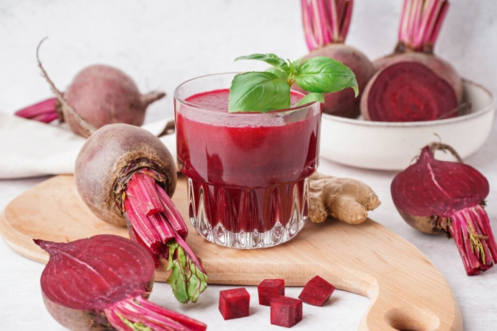 Suco de beterraba em copos de vidro e ao lado beterrabas cortadas ao meio e em cubos
