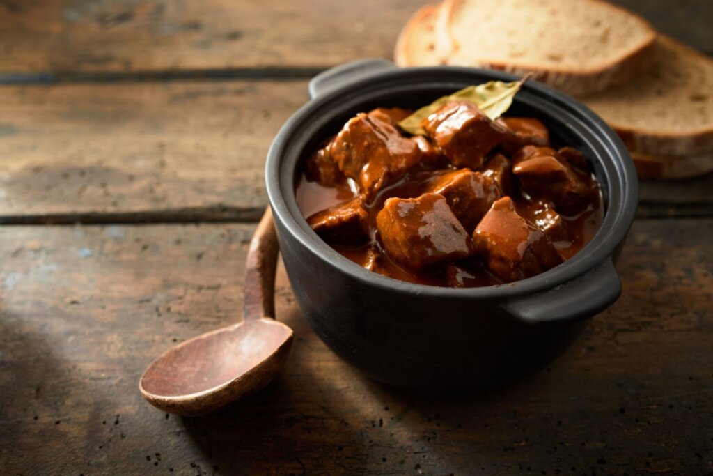 Carne de panela com cerveja preta em uma panela preta sobre uma mesa de madeira 