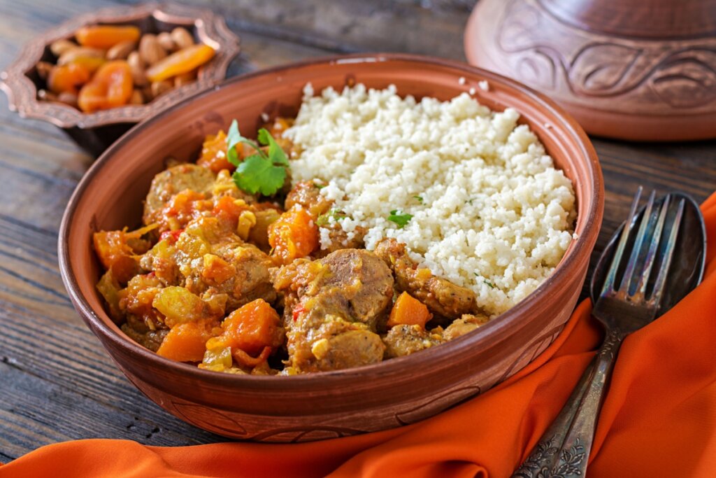 Tajine de cordeiro com abóbora e cuscuz marroquino em recipiente de cerâmica