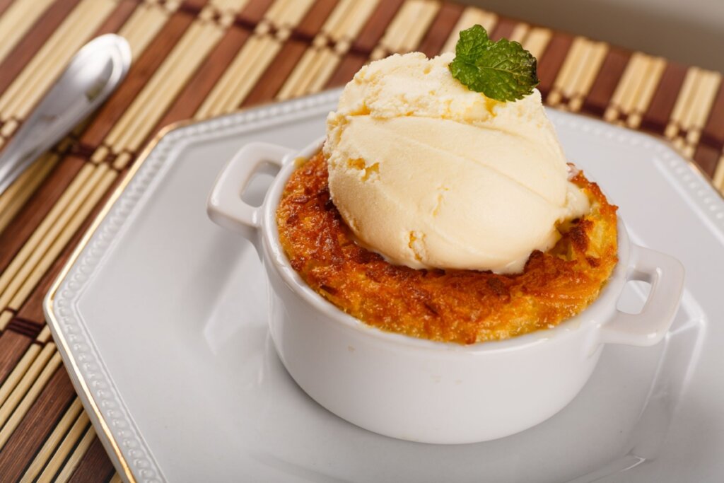 Panelinha branca de porcelana com cocada e sorvete de creme em cima 
