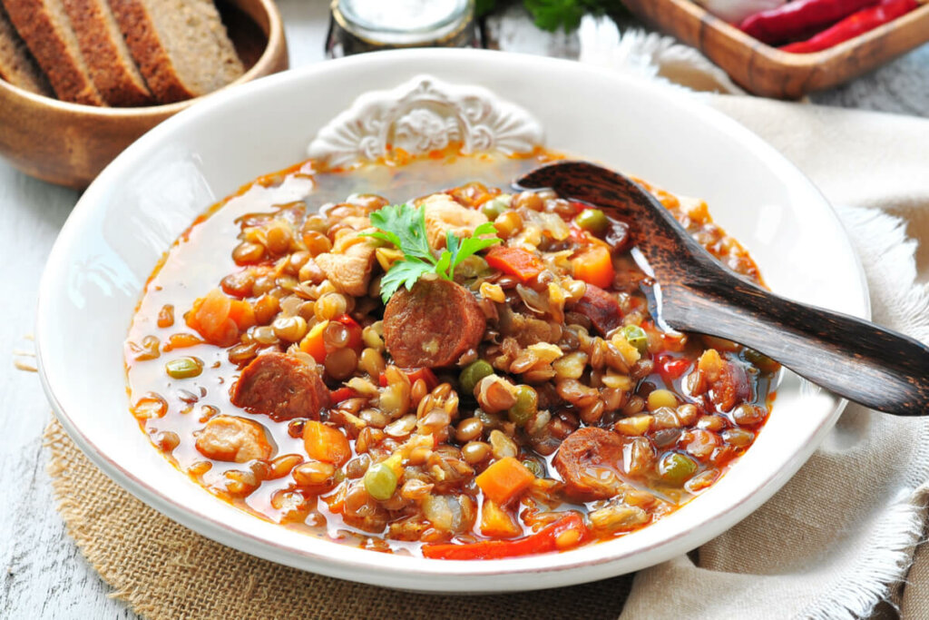 Prato branco com lentilha, cenoura, ervilha, frango e linguiça calabresa