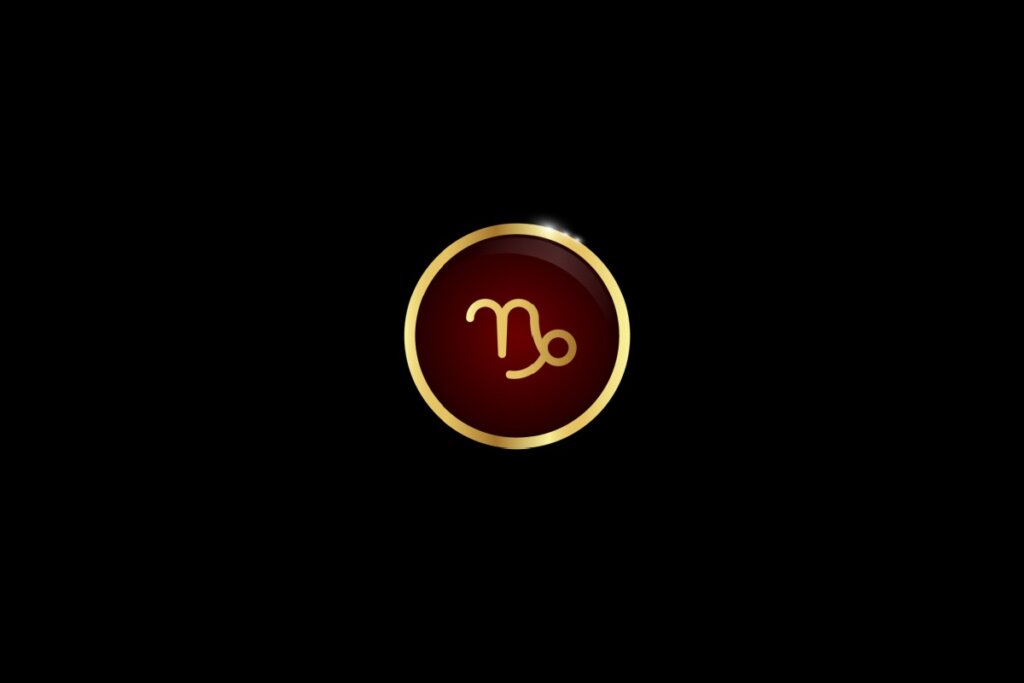 Ilustração do signo de capricórnio dentro de um círculo dourado, iluminado com uma luz vermelha, em um fundo preto