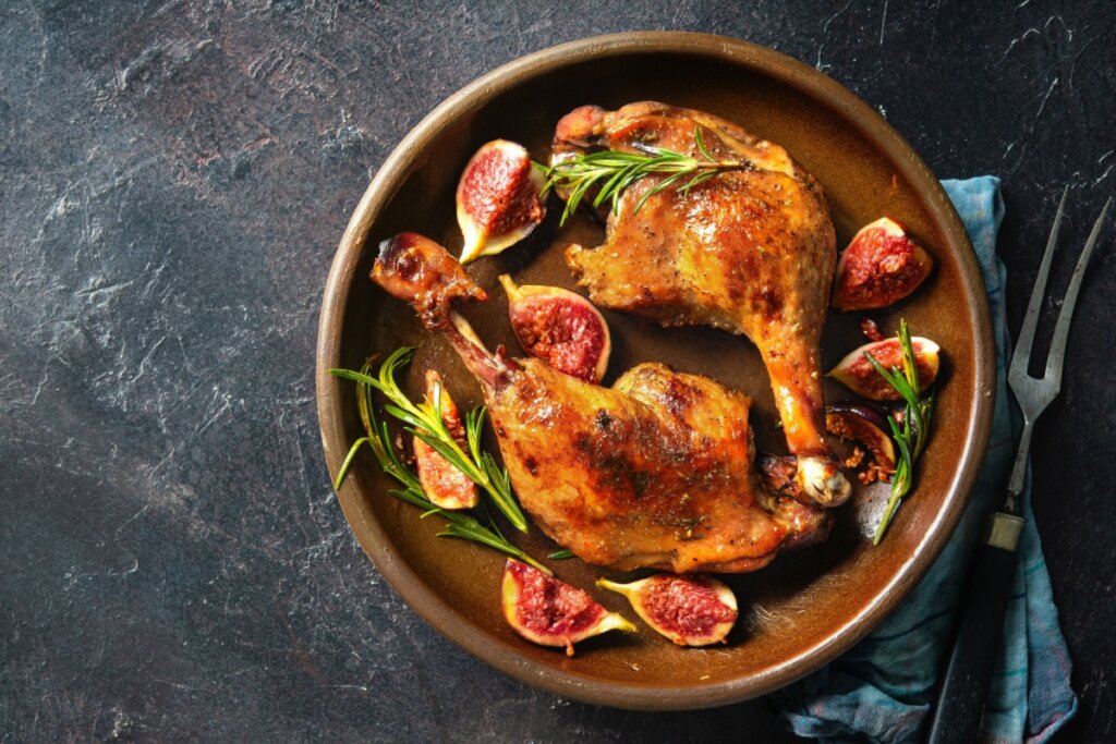 prato marrom com duas sobrecoxas de frango assadas com figo em volta