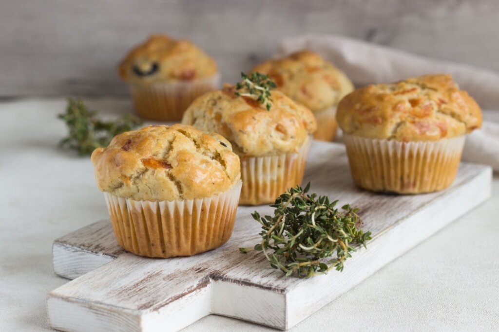Muffins de frango em tábua branca ao lado de ervas