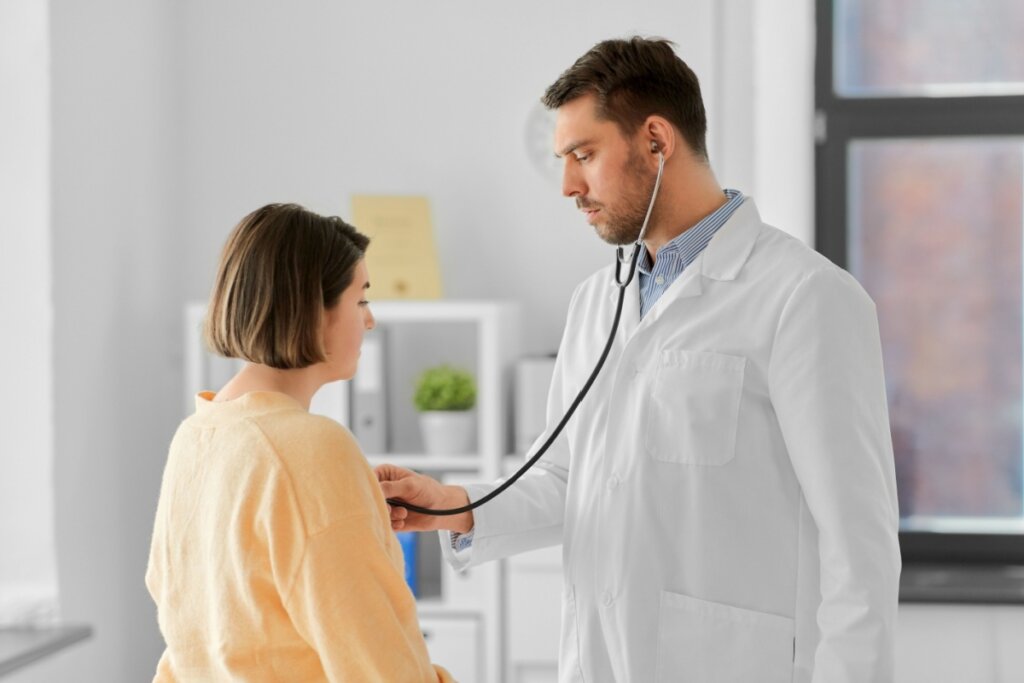 Médico com estetoscópio em paciente durante consulta cardiológica em consultório