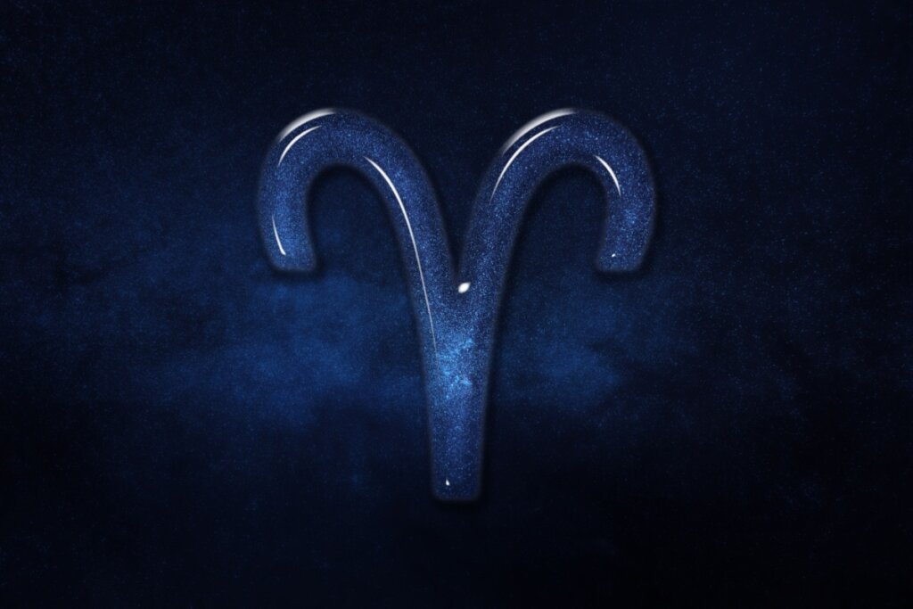 Representação do símbolo de Áries com uma textura interna de galáxia azul vibrante e bordas arredondadas como vidro, lembrando os chifres de um carneiro, sobre um fundo de céu noturno azul-escuro profundo e estrelado.
