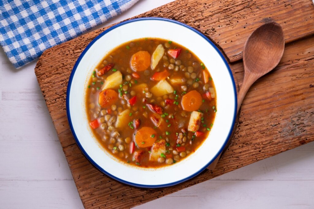 Sopa de lentilhas picantes com legumes e batatas em prato branco com borda azul