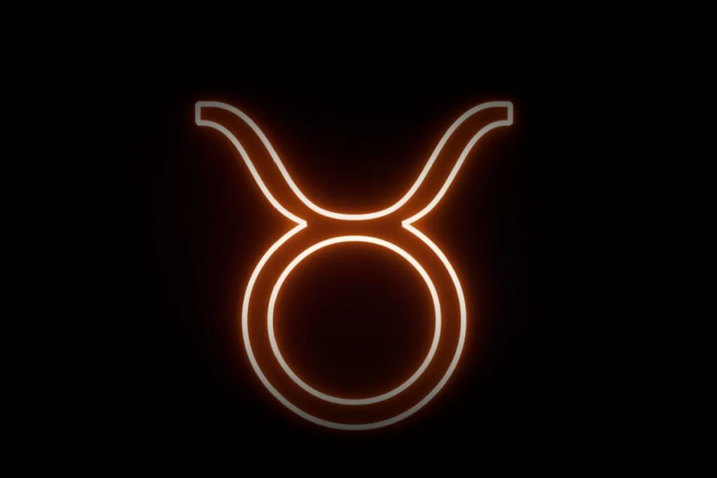 Ilustração digital do símbolo de Touro (um círculo encimado por dois chifres curvos). O design tem um aspecto de luz neon vibrante em tons alaranjados sobre um fundo preto.