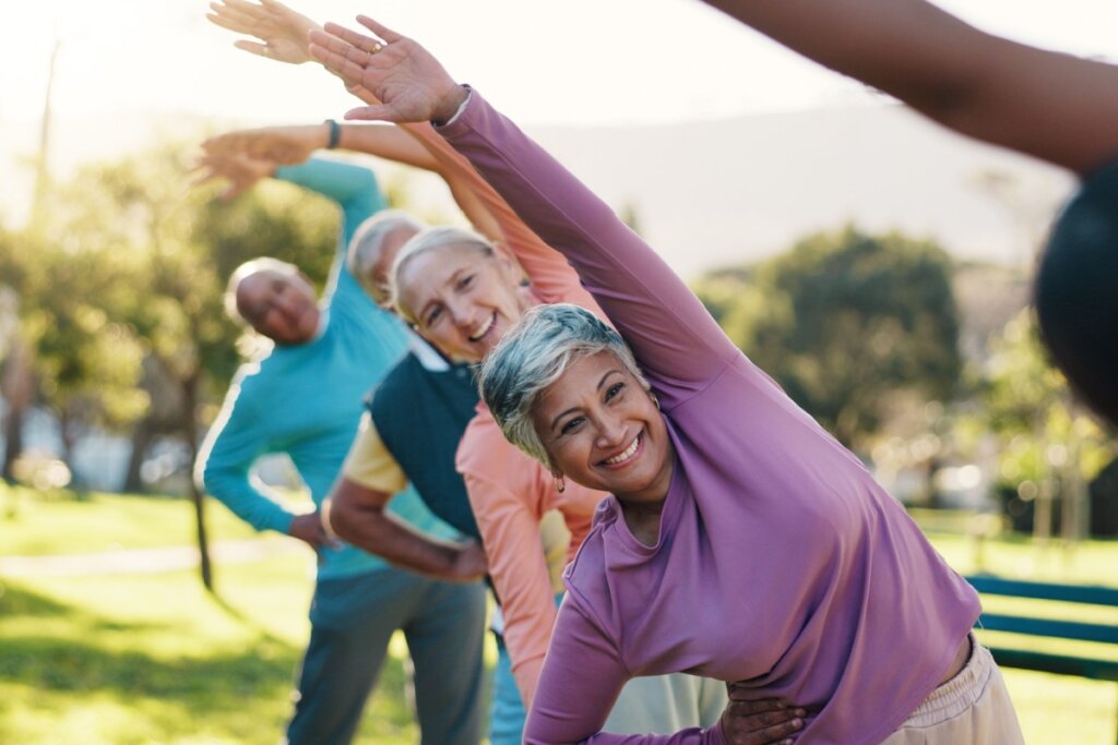 Grupo de mulheres mais velhas fazendo alongamento no parque usando roupas de academia de outono