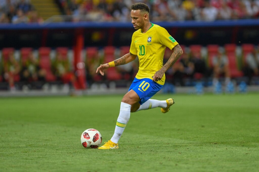 Neymar jogando bola em campo usando a camisa da seleção brasileira