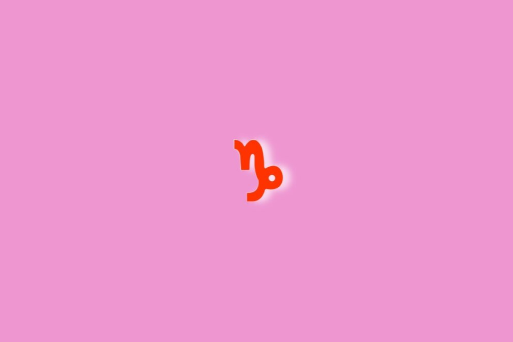 Fundo rosa com o símbolo do signo de capricórnio em vermelho no centro da imagem. Luz branca ao redor dele