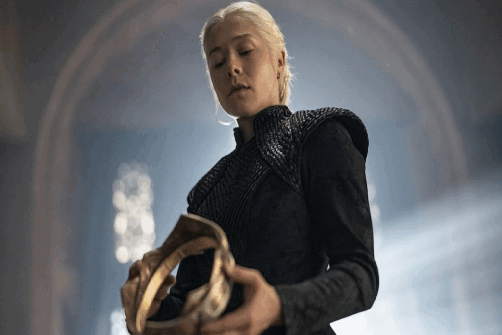 Imagem de uma mulher com o cabelo branco preso em tranças, usando roupa preta e olhando para coroa dourada na mão