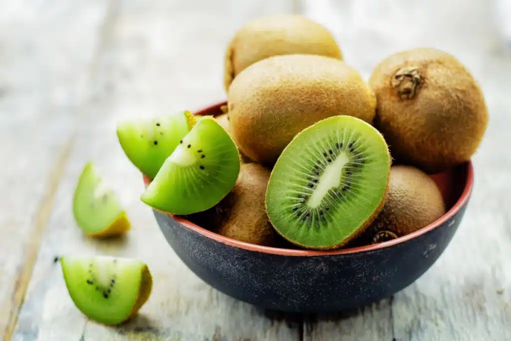 Cumbuca com kiwis, com uma metade cortada e a outra metade cortada em gomos.