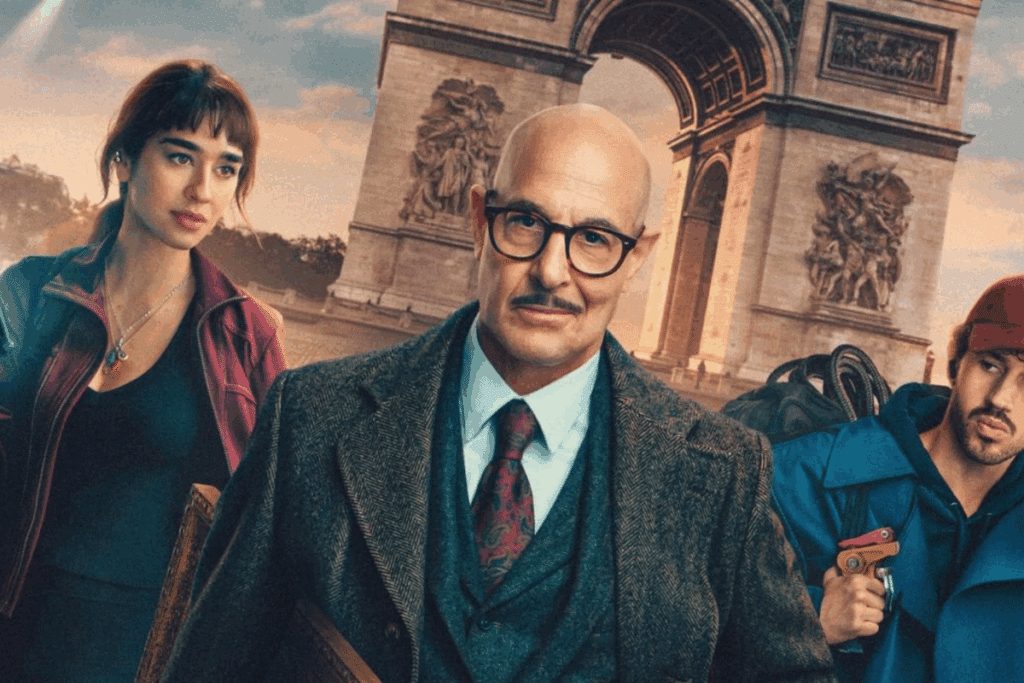 Stanley Tucci, de óculos, bigode e terno, está em primeiro plano diante do Arco do Triunfo, em Paris. Ao lado dele estão uma jovem de jaqueta vinho segurando um rádio comunicador e um jovem de boné vermelho e jaqueta azul segurando uma ferramenta.