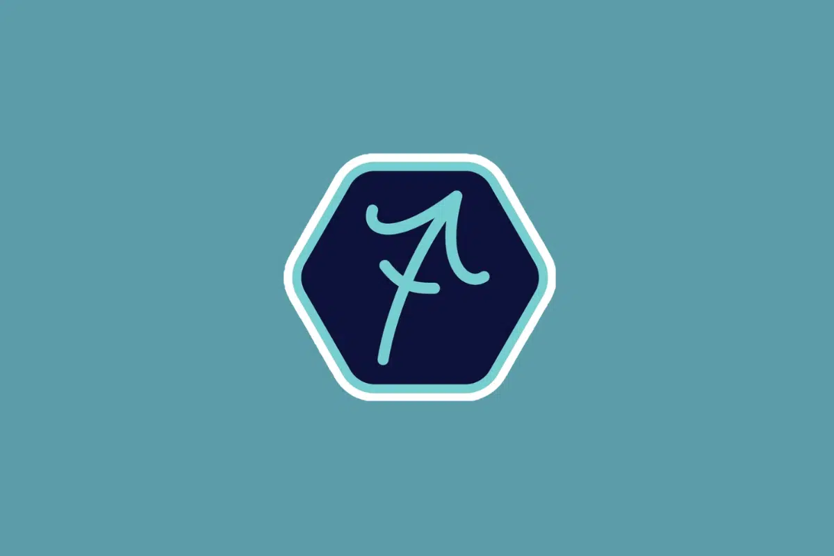Ilustração minimalista do símbolo do signo de sagitário em tom azul-claro, centralizada dentro de um hexágono azul-escuro com borda branca e azul. O fundo da imagem é em um tom sólido de azul-turquesa