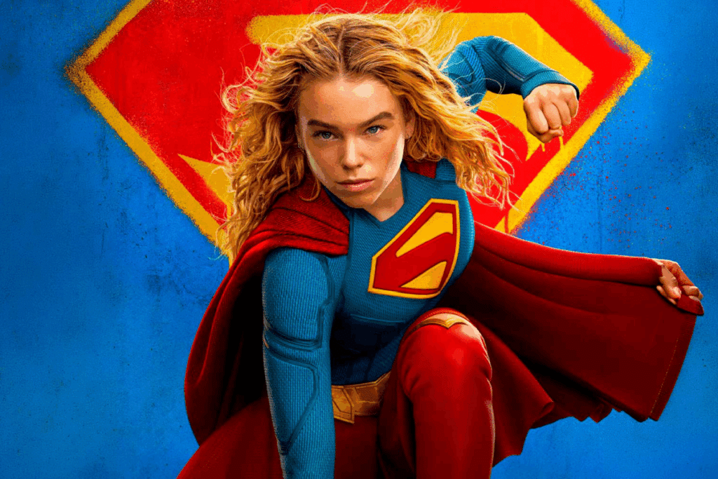 Super-heroína com uniforme azul e vermelho em pose de ação diante de um símbolo estilizado ao fundo