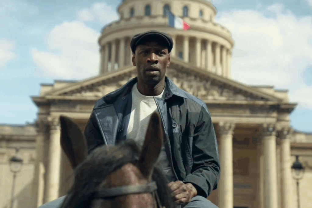 Um homem negro usando boina e jaqueta escura está montado a cavalo em frente a um grande prédio histórico com a bandeira da França no topo.